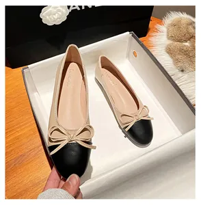 Detailansicht der beigen Ballerinas mit schwarzer Kappe und Schleife im Schuhkarton