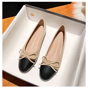 Detailansicht beige Ballerinas mit schwarzer Kappe und Schleife in einer Geschenkbox