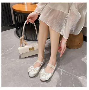 Détail macro de ballerines en satin blanc avec un grand nœud et une bride élastique