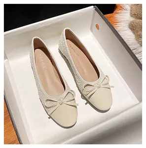 Detailansicht beige Tweed Ballerinas mit Schleife in einem minimalistischen Schuhkarton