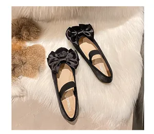Détail de ballerines noires avec un grand nœud en satin et une bride élastique