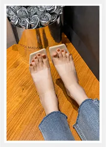 Nude Sandalen mit quadratischer Zehenpartie aus transparentem PVC auf einer Holzfläche