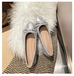Nahaufnahme silberner Ballerinas mit matter Kappe und zarter Schleifenverzierung