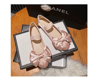 Gros plan sur les ballerines Mary Jane en satin rose avec grand nœud et sangle élastique