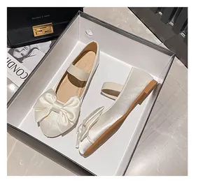 Vue de dessus de ballerines Mary Jane en satin crème avec un grand nœud dans leur boîte
