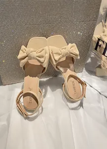 Detalle del elegante lazo beige en la sandalia de tacón bajo con tela suave
