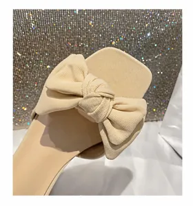 Detalle de la textura acanalada y el lazo 3D en la sandalia beige de punta cuadrada