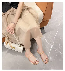 Detailed view of nude toe-loop flat sandals featuring a large square rhinestone decoration