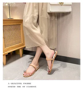 Detail of beige rhinestone toe-ring sandals featuring sparkling buckle and shiny sole edge