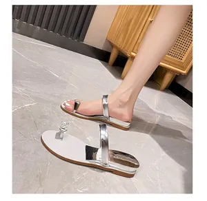 Detail showing shiny silver wedge flip-flops with rhinestone buckle on casual model feet