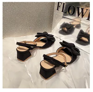 Primer plano de elegantes sandalias de ante negro con detalle de lazo y correa