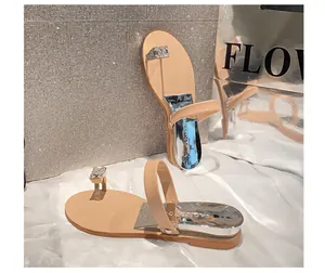 Close-up of beige flat thong sandals featuring a square rhinestone buckle and silver heel