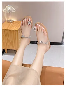 Nahaufnahme eleganter Sommer Zehen-Sandalen mit funkelnden Strassblumen und Klarsichtriemen