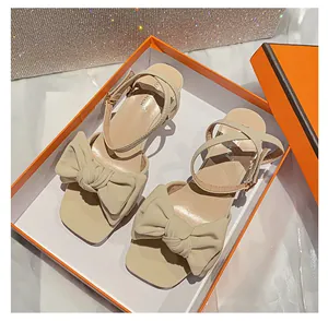 Detalle del lazo beige y la correa del tobillo en sandalias elegantes de punta cuadrada