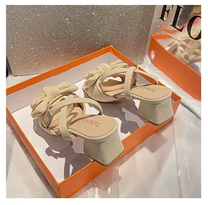 Detalle de sandalias beige con lazo y tacón cuadrado en una elegante caja de regalo