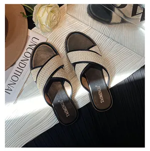 Detail der geflochtenen Stroh-Überkreuzgurte mit schwarzer Lederpaspel an flachen Sandalen