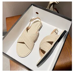 Detail der cremefarbenen gewebten Kreuzriemen und der verstellbaren Schnalle der Sandalen