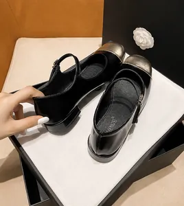 Detail view of black patent leather Mary Jane flats with gold metal capped round toes
