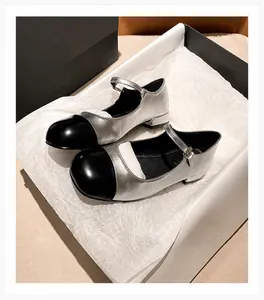 Detail of silver metallic Mary Jane shoes with black cap toe and buckled strap