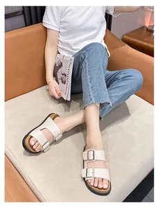Detail of a chic cream leather strap slide sandal with silver metal buckles on a cork sole