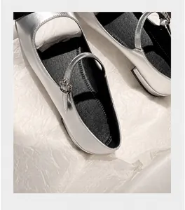 Close-up of silver Mary Jane flats featuring a rhinestone strap and glossy metallic finish