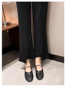 Gros plan de ballerines Mary Jane noires portées avec un pantalon fendu tendance