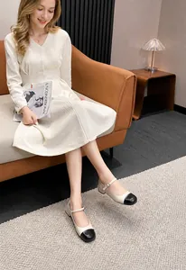 Detail of two-tone Mary Jane flats with pearl buckle strap on an orange leather sofa