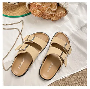Overhead shot of beige dual-strap slide sandals with metal buckles on summer fabric
