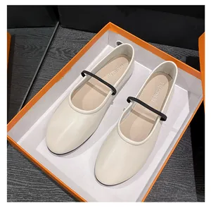 Vue de dessus de ballerines Mary Jane blanches à bride noire dans une boîte orange