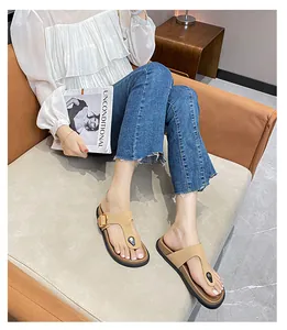 On-foot view of khaki leather flip-flops with gold buckles and chic metal details