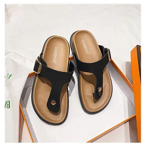 Detail of black T-strap Birkenstock sandals with gold buckles and matte finish texture