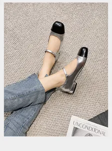 Close-up of silver Mary Jane shoes with black cap toe on a woven carpet surface
