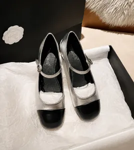 Close-up of silver Mary Jane flat shoes with contrast black round toe and buckle strap