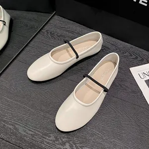 Ballerines Mary Jane beiges chic à bout rond avec fine bride noire sur bois sombre