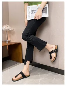 Detail of black leather straps and gold buckle on stylish summer flip-flop sandals