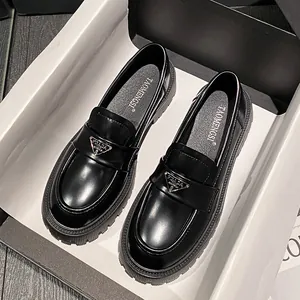 Black glossy platform loafers with metal triangle plaque in a designer gift box