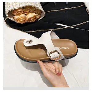 Detail of white leather thong sandal with gold buckle and metallic toe ornament