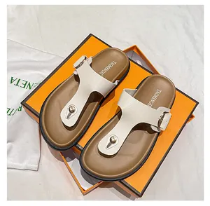 Detail of cream leather flip-flop with gold buckle and rivets on orange luxury box