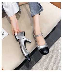 Detailed close-up of metallic silver Mary Jane shoes with black patent leather cap toe