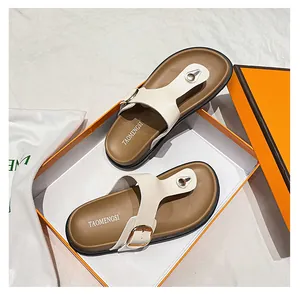 Detailed shot of white textured strap toe-loop sandal with gold buckle in orange box