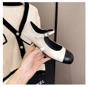 Detail of Mary Jane shoe with black cap toe and rhinestone buckle on cream leather strap