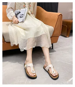 Close-up of beige leather T-strap flip flops with metal buckle on a cork platform sole