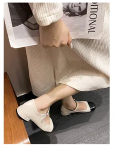 Detail of cream and black two-tone Mary Jane flats with leather texture and strap