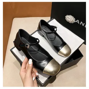 Detail shot of black leather Mary Jane flat shoes with gold cap-toe and rhinestone buckle