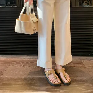 Women's brown leather platform thong sandals with gold buckle on wooden floor