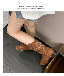 Detalle de botas western de ante marrón con bordado ondulado y tacón bloque estable