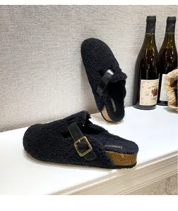 Close-up of black fuzzy mule shoes with leather strap and golden metal buckle detail