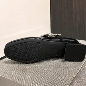 Detail der rutschfesten Gummisohle und Strass-Schnalle an schwarzen Lacklederschuhen