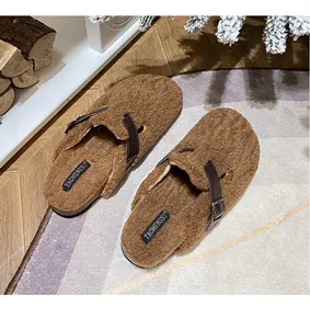 Close-up of brown faux shearling Boston clogs with leather strap on a cozy rug