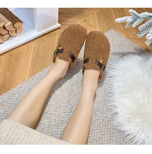 Close-up of cozy brown lamb wool slippers with leather strap on vintage wooden floor
